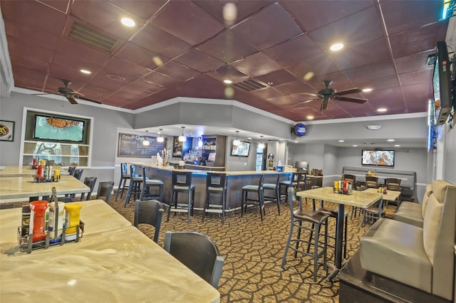 carpeted dining space featuring a community bar, visible vents, ceiling fan, and ornamental molding