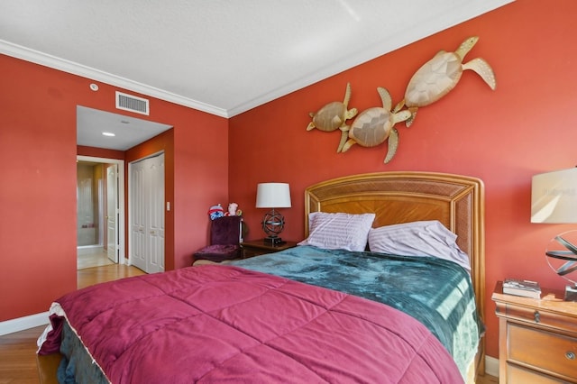 bedroom featuring a closet, visible vents, ornamental molding, wood finished floors, and baseboards