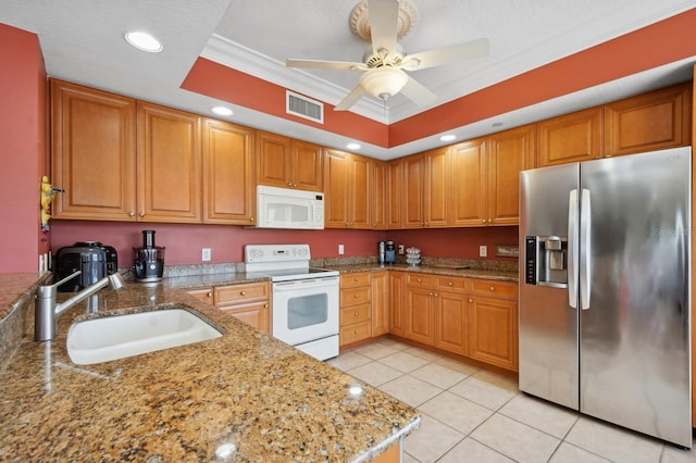 kitchen with light stone counters, white appliances, a sink, visible vents, and a tray ceiling