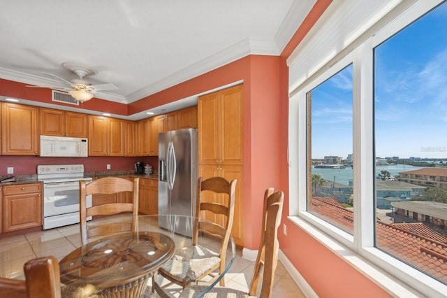 kitchen with light tile patterned floors, white appliances, a water view, visible vents, and dark countertops