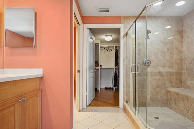 bathroom featuring tile patterned flooring, visible vents, a shower stall, and vanity