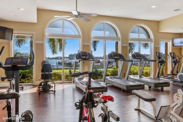 workout area with a water view, wood finished floors, a ceiling fan, and recessed lighting