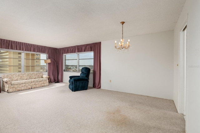 living area with a textured ceiling, carpet flooring, and a chandelier