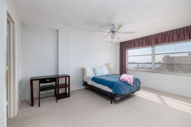 bedroom with a textured ceiling, ceiling fan, and light colored carpet