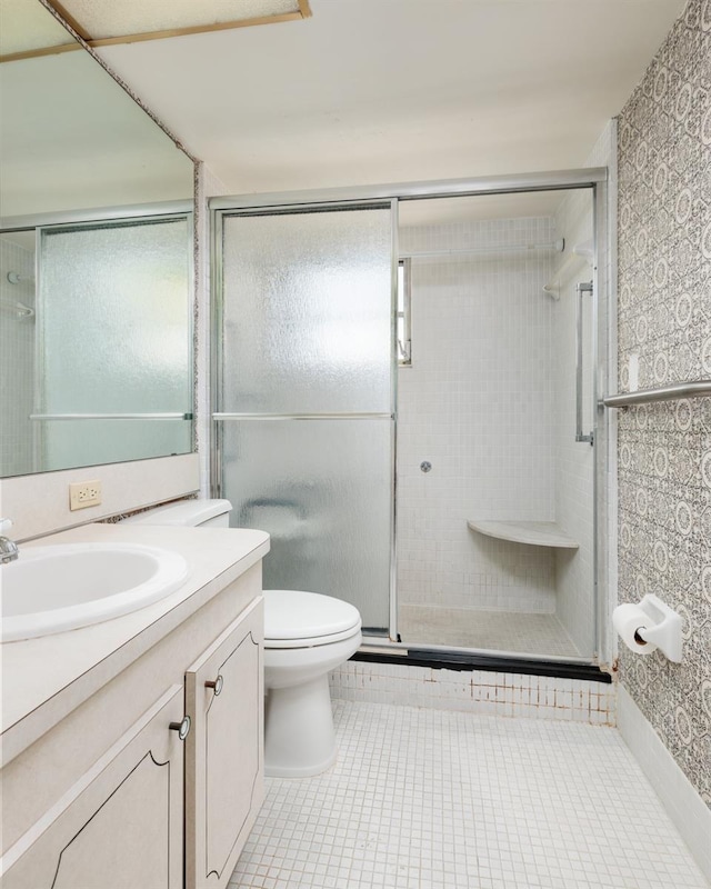 bathroom with tile patterned floors, a shower with shower door, toilet, and vanity