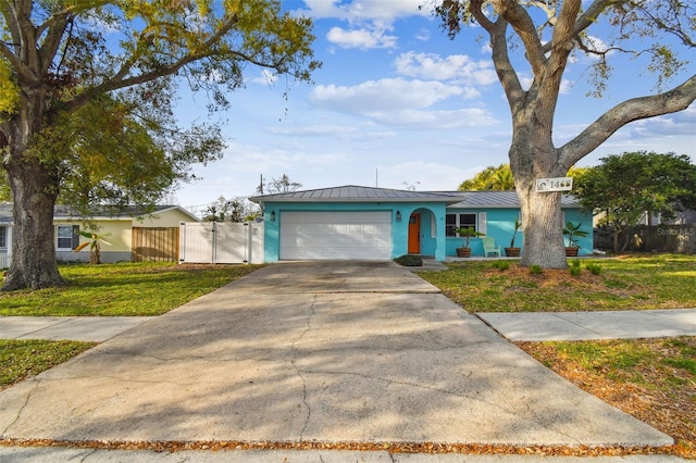 view of front facade with concrete driveway, metal roof, an attached garage, a standing seam roof, and fence