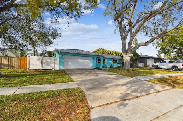 view of front of home with metal roof, an attached garage, fence, concrete driveway, and a gate