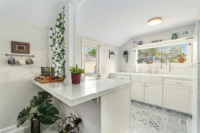 kitchen featuring lofted ceiling, dishwasher, a kitchen breakfast bar, kitchen peninsula, and white cabinets