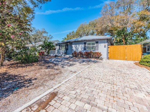 single story home featuring a gate and metal roof