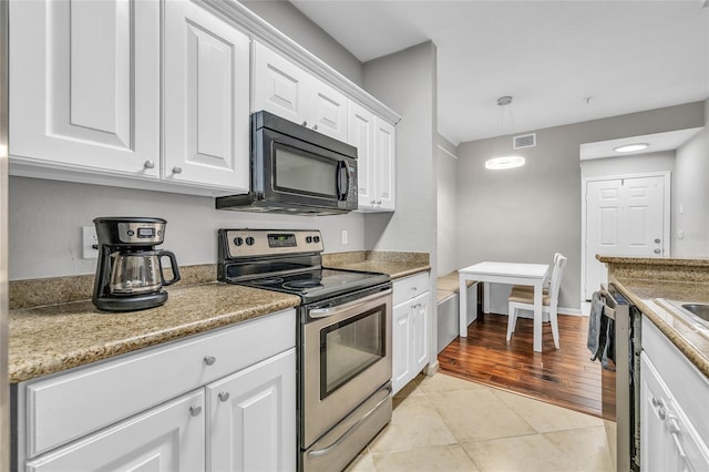 kitchen with visible vents, pendant lighting, light tile patterned floors, appliances with stainless steel finishes, and white cabinetry