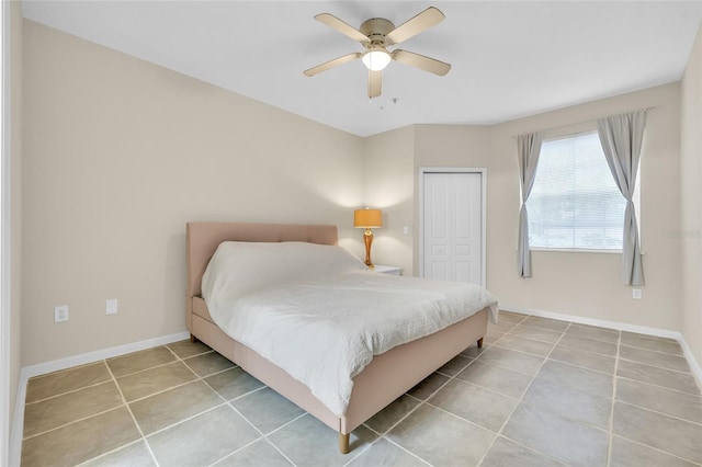 tiled bedroom with a closet, ceiling fan, and baseboards