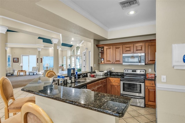 kitchen with visible vents, a peninsula, stainless steel appliances, and decorative columns