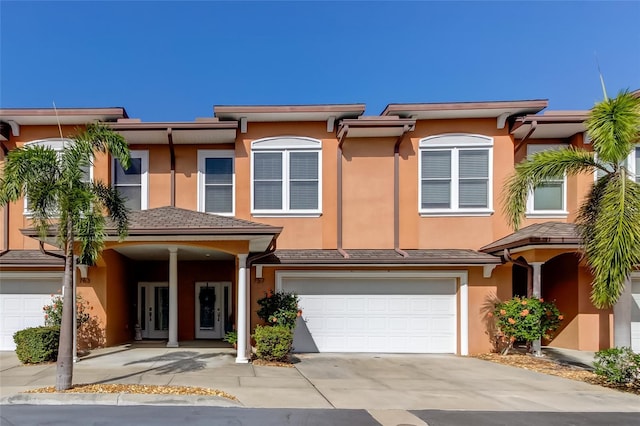 multi unit property with an attached garage, driveway, and stucco siding