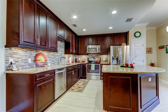 kitchen with a sink, appliances with stainless steel finishes, a kitchen island, and visible vents