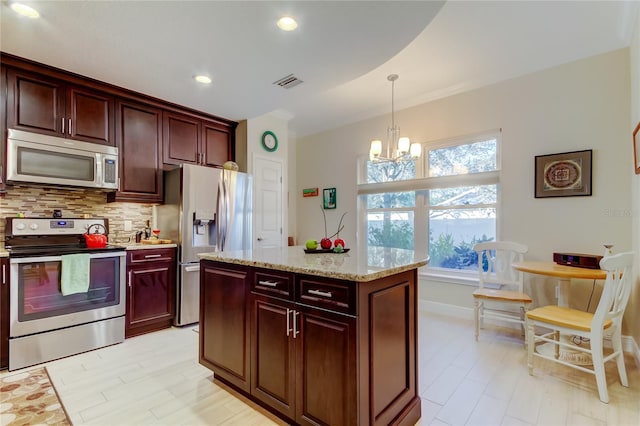 kitchen featuring visible vents, decorative backsplash, hanging light fixtures, light stone countertops, and stainless steel appliances