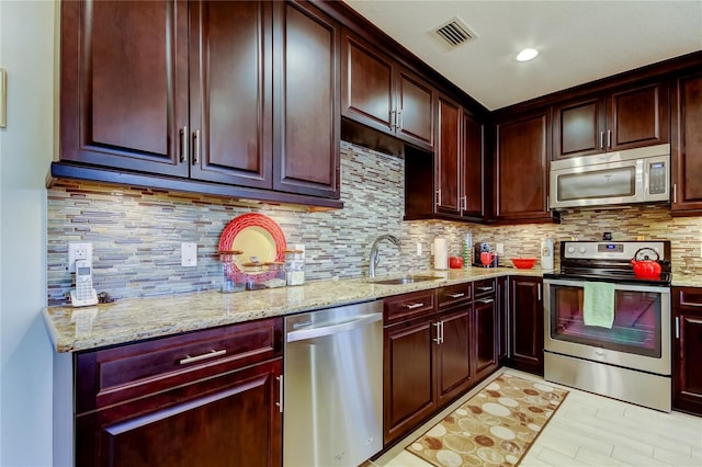 kitchen with tasteful backsplash, visible vents, appliances with stainless steel finishes, light stone countertops, and a sink