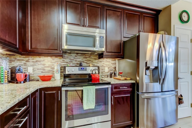 kitchen with stainless steel appliances, backsplash, and light stone countertops