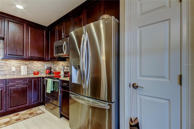 kitchen featuring stainless steel appliances, dark brown cabinets, backsplash, and light stone counters