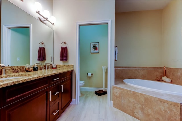 bathroom featuring toilet, a sink, baseboards, a bath, and double vanity