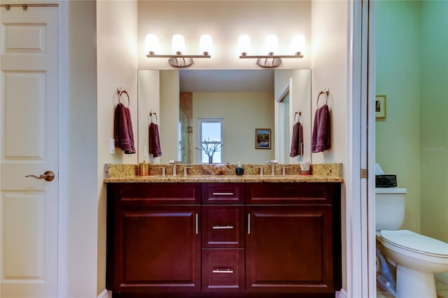 bathroom with double vanity, a stall shower, a sink, and toilet