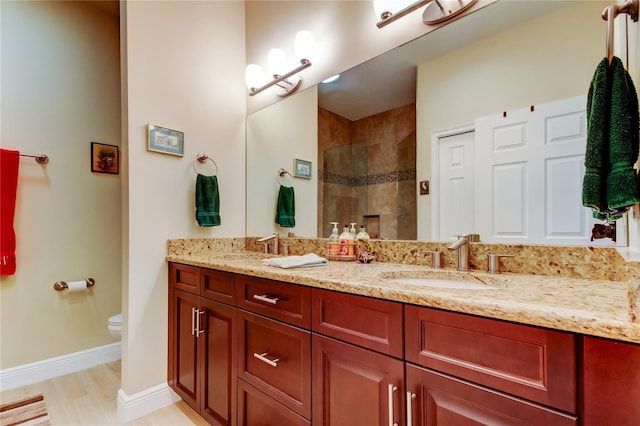 bathroom featuring double vanity, toilet, walk in shower, and a sink