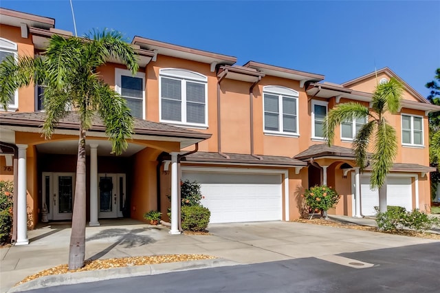 townhome / multi-family property with driveway, an attached garage, and stucco siding