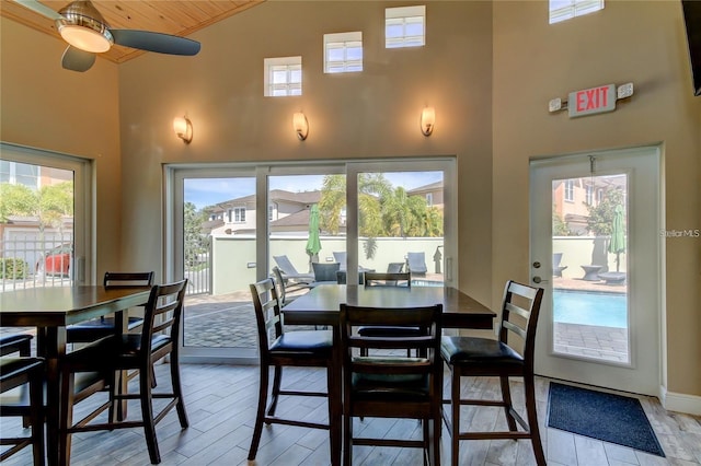 dining room with light wood-type flooring, high vaulted ceiling, and a ceiling fan