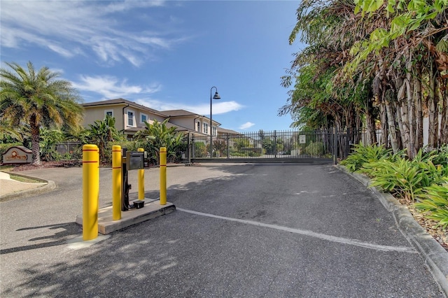 view of road with street lighting, a gate, a gated entry, and curbs