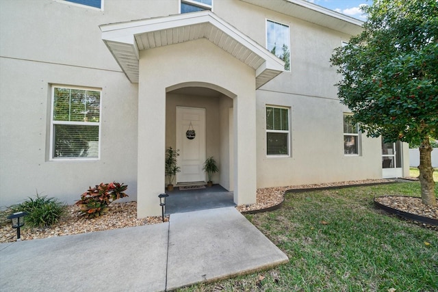 doorway to property featuring a lawn and stucco siding