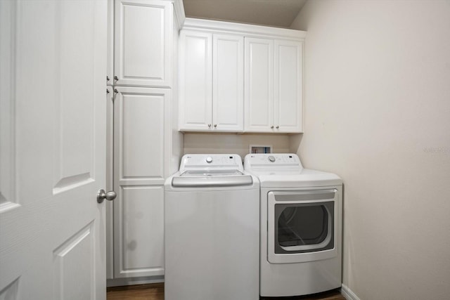 laundry area featuring dark wood-style flooring, cabinet space, baseboards, and washing machine and clothes dryer