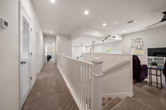 hallway with carpet floors, an upstairs landing, visible vents, and recessed lighting