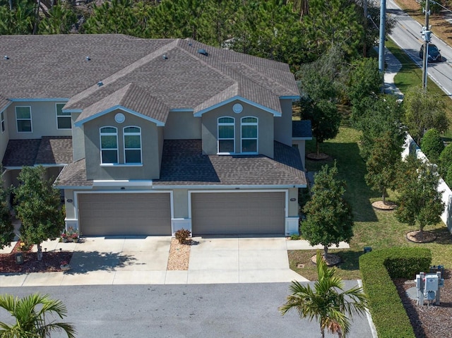 exterior space with an attached garage, roof with shingles, concrete driveway, and stucco siding