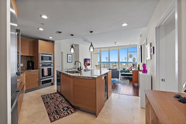 kitchen with tasteful backsplash, modern cabinets, appliances with stainless steel finishes, brown cabinets, and a sink