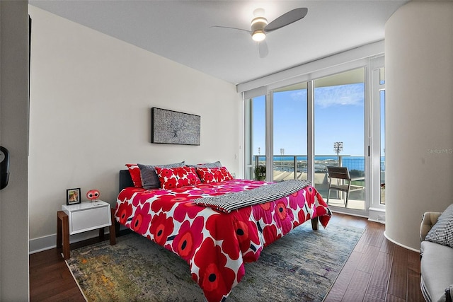 bedroom with access to exterior, expansive windows, baseboards, and wood finished floors