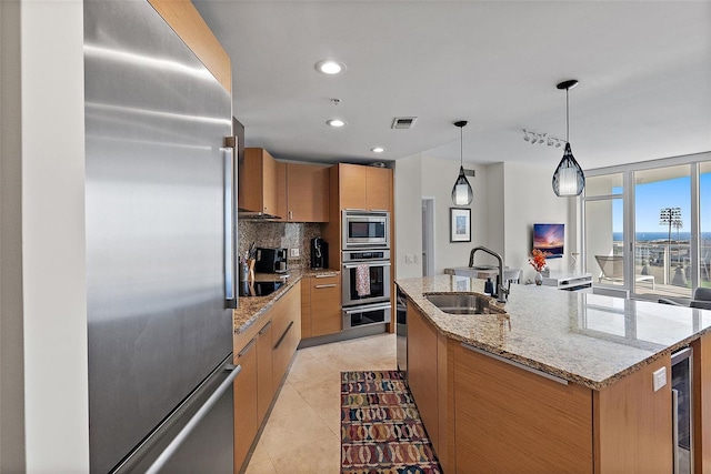 kitchen featuring tasteful backsplash, visible vents, wine cooler, appliances with stainless steel finishes, and a sink