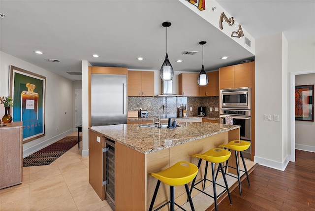 kitchen with tasteful backsplash, visible vents, a sink, and built in appliances