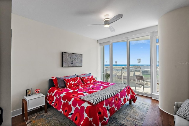 bedroom featuring baseboards, ceiling fan, wood finished floors, a water view, and access to exterior