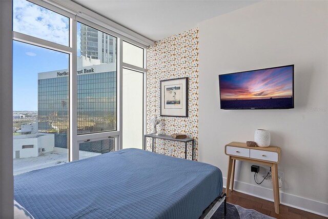 bedroom with expansive windows, baseboards, and wood finished floors