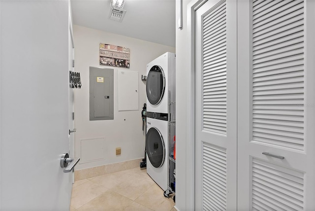 laundry area featuring visible vents, light tile patterned flooring, stacked washing maching and dryer, laundry area, and electric panel