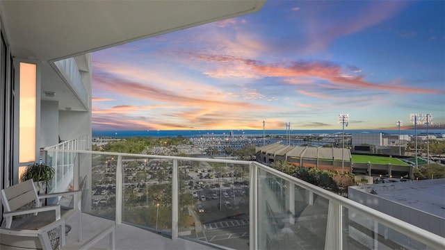 balcony at dusk featuring a water view