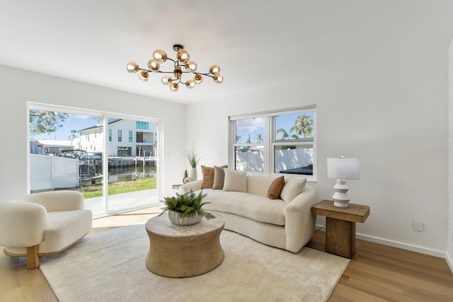 living room featuring a notable chandelier, a healthy amount of sunlight, baseboards, and wood finished floors