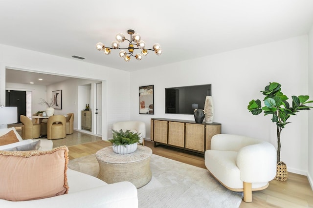 living area featuring visible vents, light wood finished floors, and a chandelier