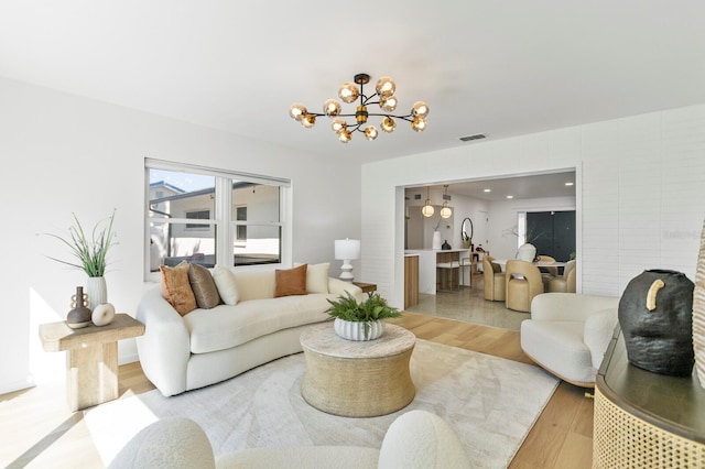 living room featuring a notable chandelier, visible vents, and wood finished floors