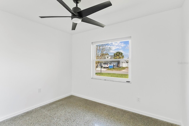 empty room featuring a ceiling fan, speckled floor, and baseboards