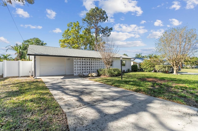 view of front of property featuring brick siding, a front lawn, fence, a garage, and driveway