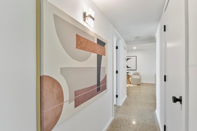 hallway featuring speckled floor and baseboards