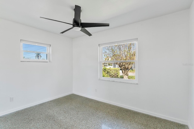 unfurnished room with speckled floor, a ceiling fan, and baseboards