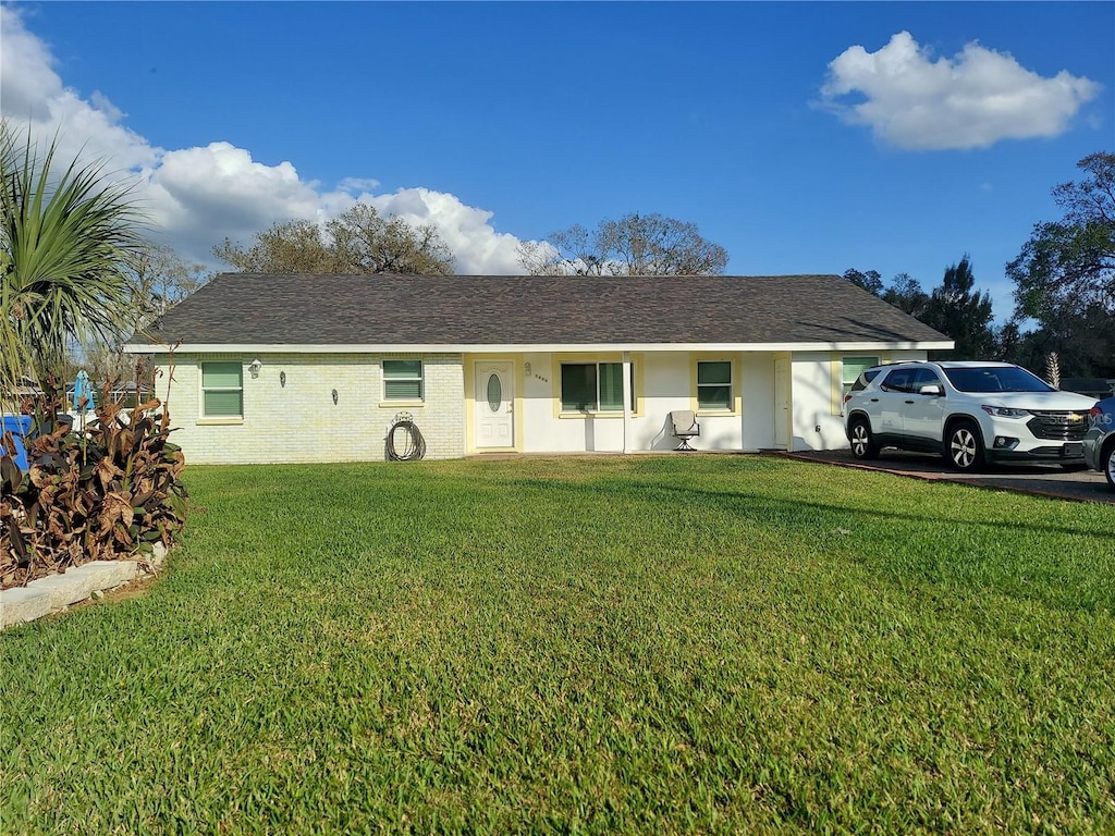 ranch-style house with roof with shingles, a front lawn, and brick siding