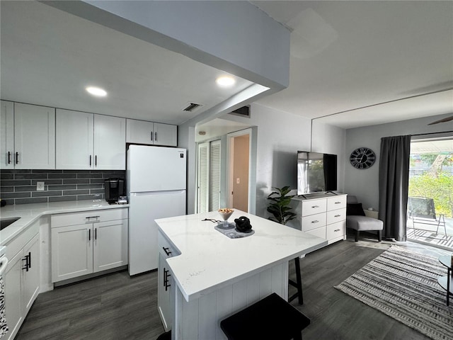 kitchen featuring white fridge, dark wood-type flooring, white cabinetry, and a center island