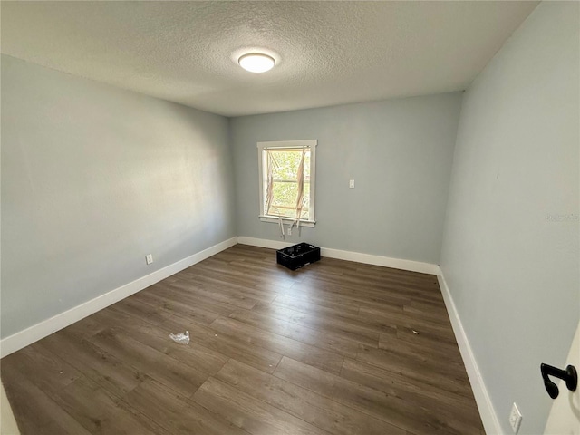 unfurnished room featuring dark wood-style floors, baseboards, and a textured ceiling